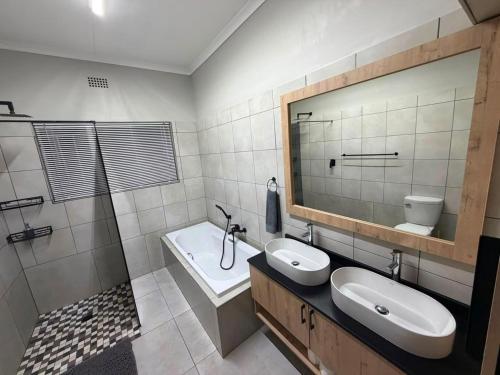 a bathroom with two sinks and a tub and a mirror at Green Haven Waitara in Tzaneen