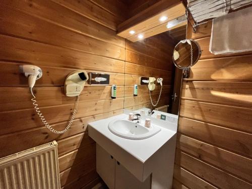 a bathroom with a sink and a phone at Logis - Hôtel & restaurant Les Trois Fontaines in Marconne