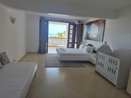a bedroom with a white bed and a balcony at Ocean View Apartment D5 in Mombasa