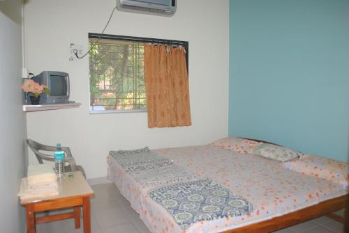 a bedroom with a bed and a tv and a table at Hotel Anjali Lodge Malvan in Malvan