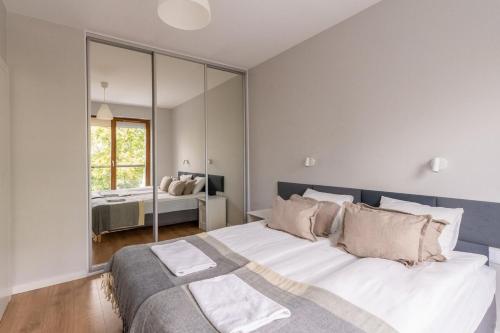a bedroom with a large bed and a mirror at Warsaw Concierge Gocławek in Warsaw