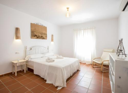 a white bedroom with a bed and a chair at Casa Rita in San Ferrán de ses Roques