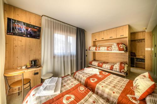 a hotel room with two beds and a desk at Hotel Club Funivia in Aprica