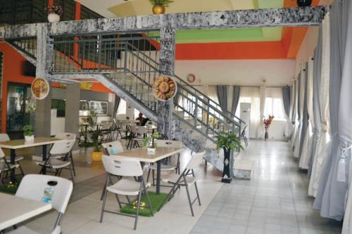 a restaurant with tables and chairs and a staircase at Andysilk Resort International in Ozu Abam