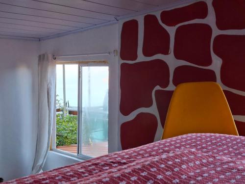 a bedroom with a bed with a yellow chair and a window at Casa de Férias Carioca in Rio de Janeiro