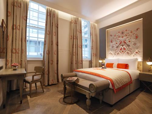 a hotel room with a bed and a desk and window at The LaLit London in London