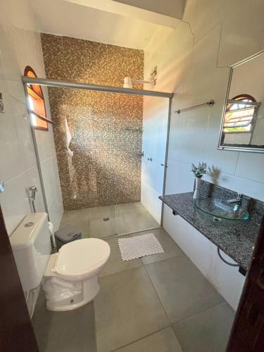 a bathroom with a toilet and a glass shower at Pousada Jardim do Éden in Serra do Cipo