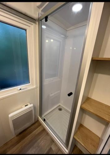 a walk in shower in a room with a window at Camping LES ARBOUSIERS Carcans in Carcans
