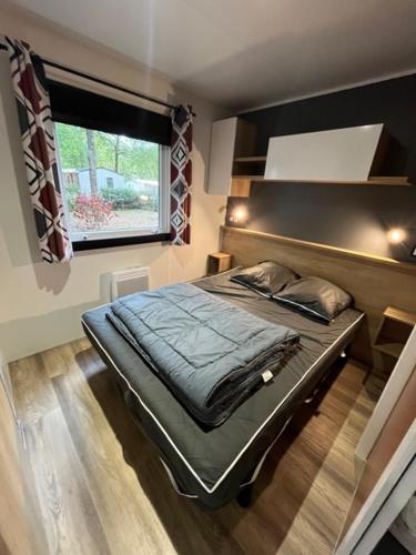 a bedroom with a bed in a room with a window at Camping LES ARBOUSIERS Carcans in Carcans