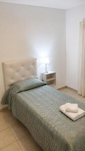 a bedroom with a bed with a blanket and a lamp at Departamento Centro Viedma in Viedma