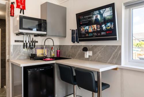 a kitchen with a counter and a tv on the wall at Cushendall Coastal Accommodation, Glens of Antrim - Beach & Mountain Access in Cushendall