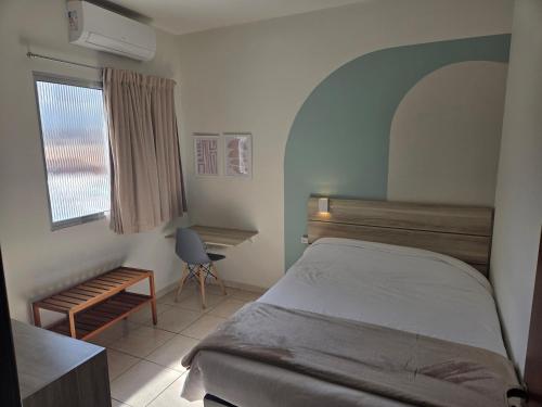 a bedroom with a bed and a desk and a window at Pousada Tokyo Plaza in Mogi das Cruzes