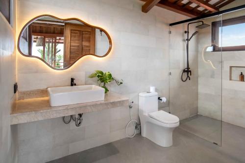 a bathroom with a sink and a toilet and a mirror at Dream Nest Bali in Munggu