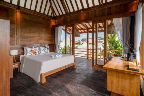 a bedroom with a bed and a desk and windows at Dream Nest Bali in Munggu
