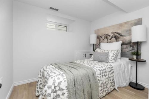 a white bedroom with a bed and a painting on the wall at Bright 2 Bedroom Suite in Windsor