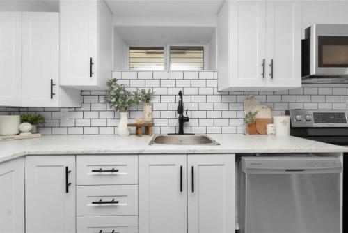 a white kitchen with white cabinets and a sink at Bright 2 Bedroom Suite in Windsor