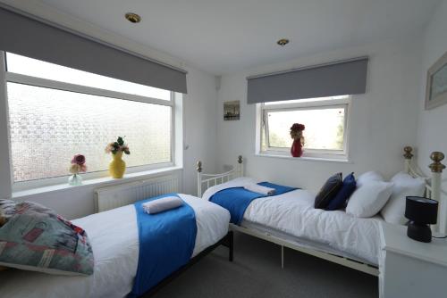 two beds in a room with two windows at Cosy 3BR House, 2 Bath, Near Luton Centre in Luton