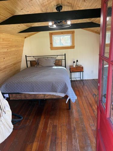a bed in a room with a wooden floor at Cozy Bethel Barn in Mongaup Valley