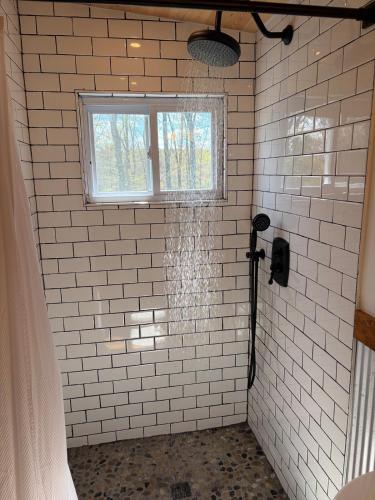 a shower in a white tiled bathroom with a window at Cozy Bethel Barn in Mongaup Valley