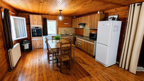 a kitchen with a table and a white refrigerator at Le chalet du mazagran in Leffincourt