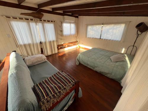 a bedroom with two beds and wooden floors and windows at Cabaña La Colmena in Tigre