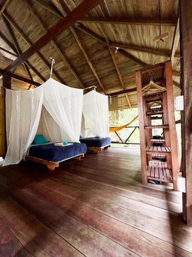 three beds in a room with a wooden floor at Casa Prana Nuquí in Nuquí