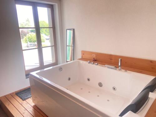 a large white bath tub in a room with a window at Bulle de rêve jacuzzi in Bulle