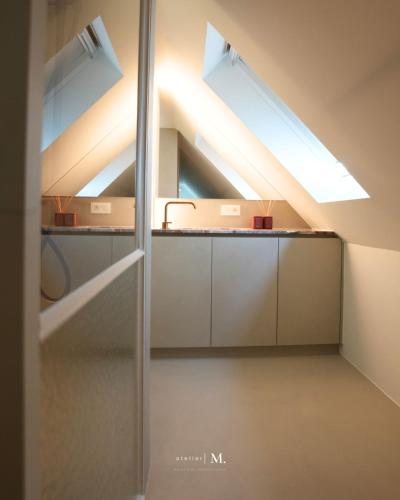 an attic kitchen with a sink and two skylights at Atelier M in Kruisem
