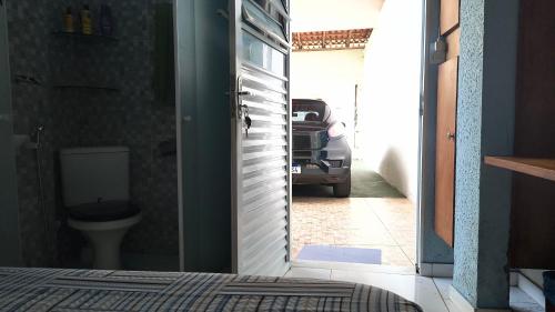 a door to a bathroom with a toilet and a car at Pousada Solar da Costa 1908 quarto com banheiro in Serra