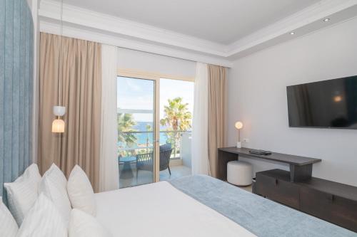 a hotel room with a bed and a desk and a balcony at Grand Blue Beach Hotel in Kardamaina