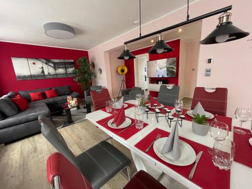 a dining room and living room with red walls at Ferienhaus BellaVita - mit großem eingezäuntem Garten - Infrarotsauna - 3 Hunde willkommen - Badesee 800m entfernt in Walkenried