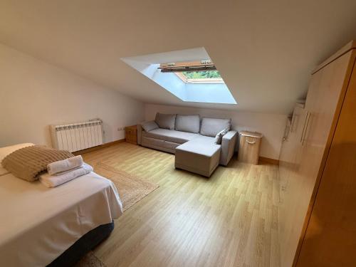 a room with a bed and a couch and a skylight at La escapada in Felechosa