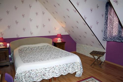 a bedroom with a bed and a purple wall at Le Logis Du Mesnil 
