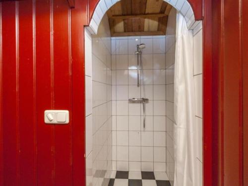 a bathroom with a shower with a red door at Hytte in Balkbrug