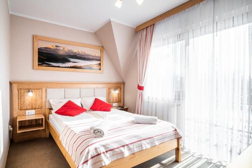 a bedroom with a bed with red pillows and a window at DW Boguń Pokoje i Apartamenty in Białka Tatrzańska