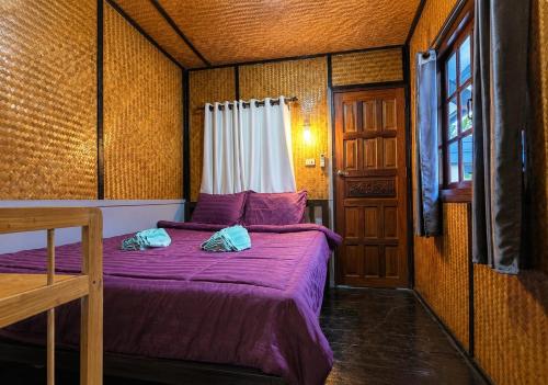 a bedroom with a bed with purple sheets and a window at SU house Koh Phangan in Thong Nai Pan Yai