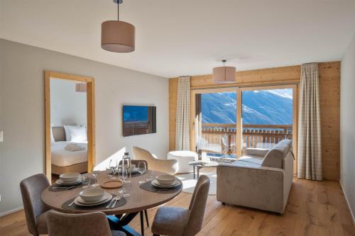 a living room with a table and a room with a view at Dent Blanche Resort - TemptingPlaces Collection in Hérémence