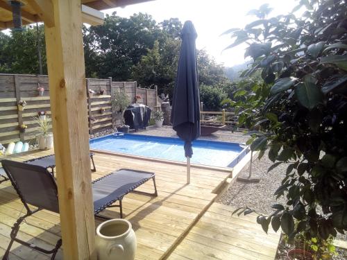 a swimming pool with an umbrella and a table and a chair and a bench at Le relais de la mine in Champagnac