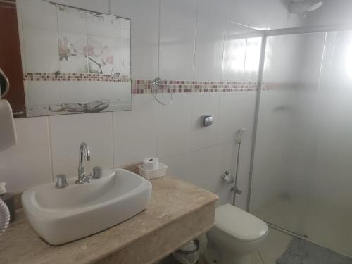 a bathroom with a sink and a toilet and a shower at Suits Recanto do Sabiá in Brotas