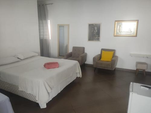 a bedroom with a bed and two chairs at Suits Recanto do Sabiá in Brotas