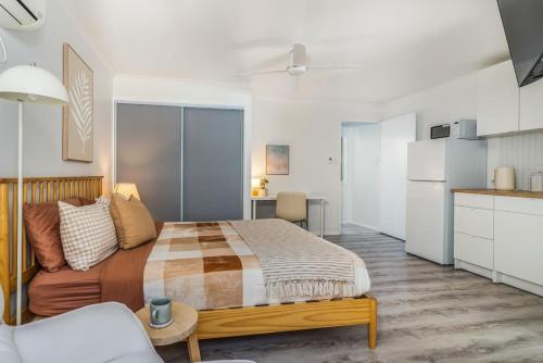 a bedroom with a large bed and a kitchen at Margate Beach Studio 4 in Redcliffe