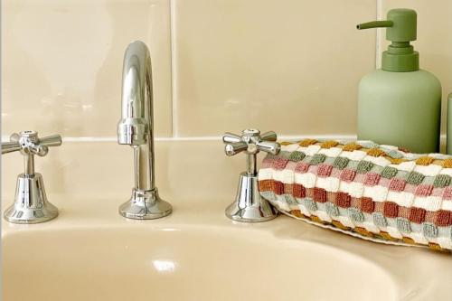 a sink with two faucets and a soap bottle at Margate Beach Studio 4 in Redcliffe