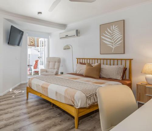 a bedroom with a large bed and a chair at Margate Beach studio 2 in Redcliffe