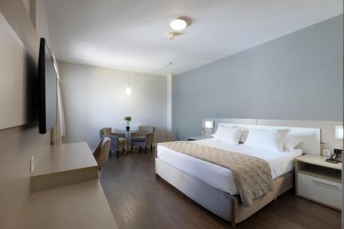 a bedroom with a large bed and a table at Hotel D'sintra in Balneário Camboriú
