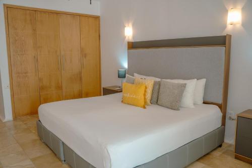 a bedroom with a large white bed with yellow pillows at NITTA 209 Elegant Apartment - Partial Sea Views in Nuevo Nayarit