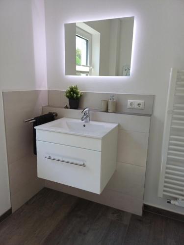 a bathroom with a white sink and a mirror at Ferienwohnung BlumenMeer in Karlshagen