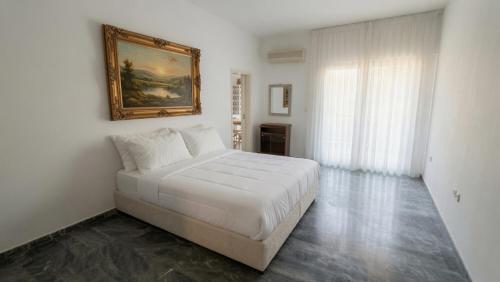 a white bedroom with a bed and a painting on the wall at Kineta Prime Suites No5 in Kineta