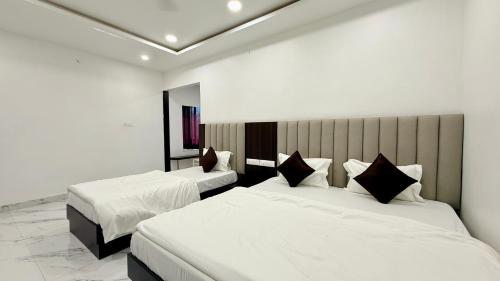 a hotel room with two beds with white sheets at Hotel Shree Banke Bihari Heritage in Maheshwar
