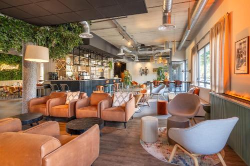 a waiting room with orange chairs and tables at Best Western Plus Hôtel de Robien in Saint-Brieuc
