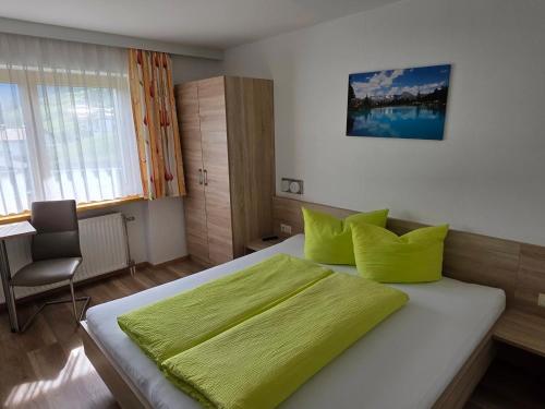 a bedroom with a bed with green sheets and a chair at Siegele - Top 1 in Kappl